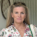 Headshot of Sam Tolhurst, co-founder of Apatchy Ltd, with long blonde hair and sunglasses on her head wearing a floral blouse.